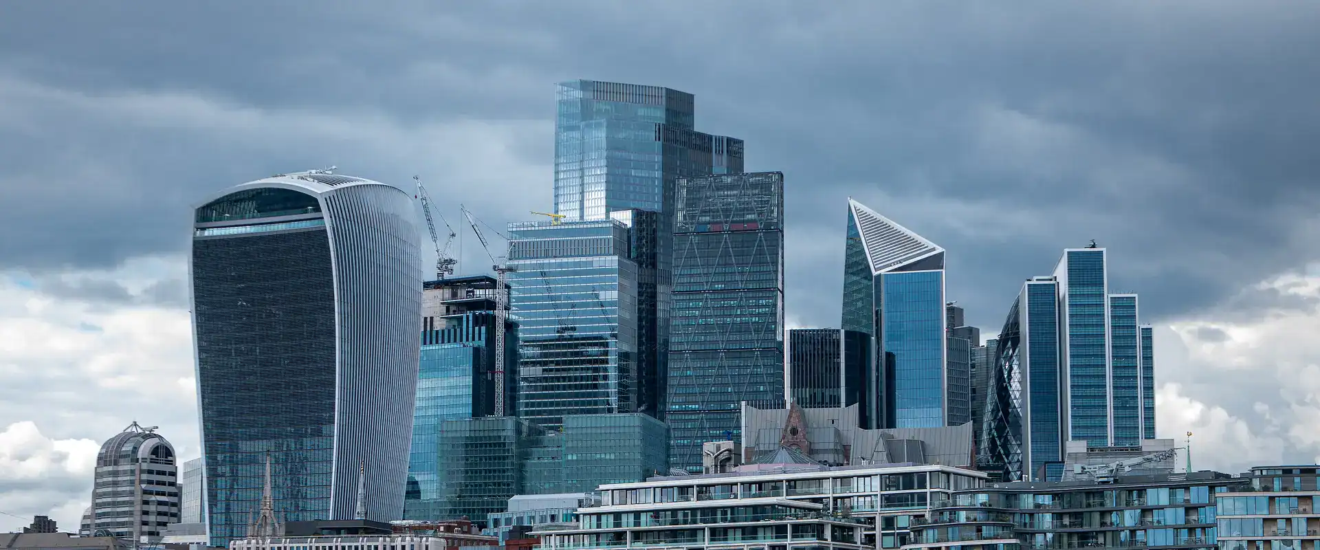 Futuristic London skyscrapers skyline with modern glass buildings under cloudy sky.