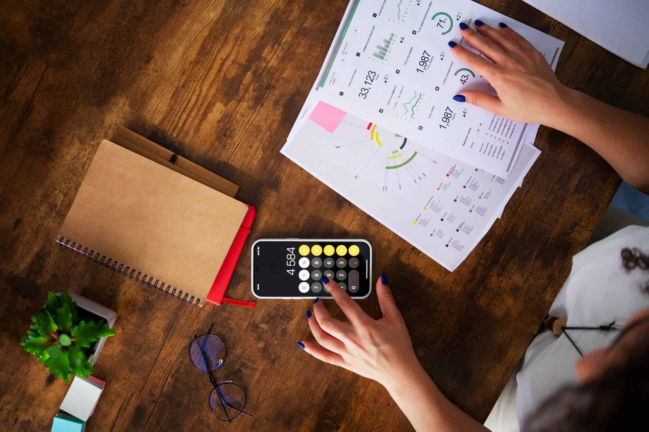 Financial planning and analysis with documents, calculator, and smartphone on wooden desk.