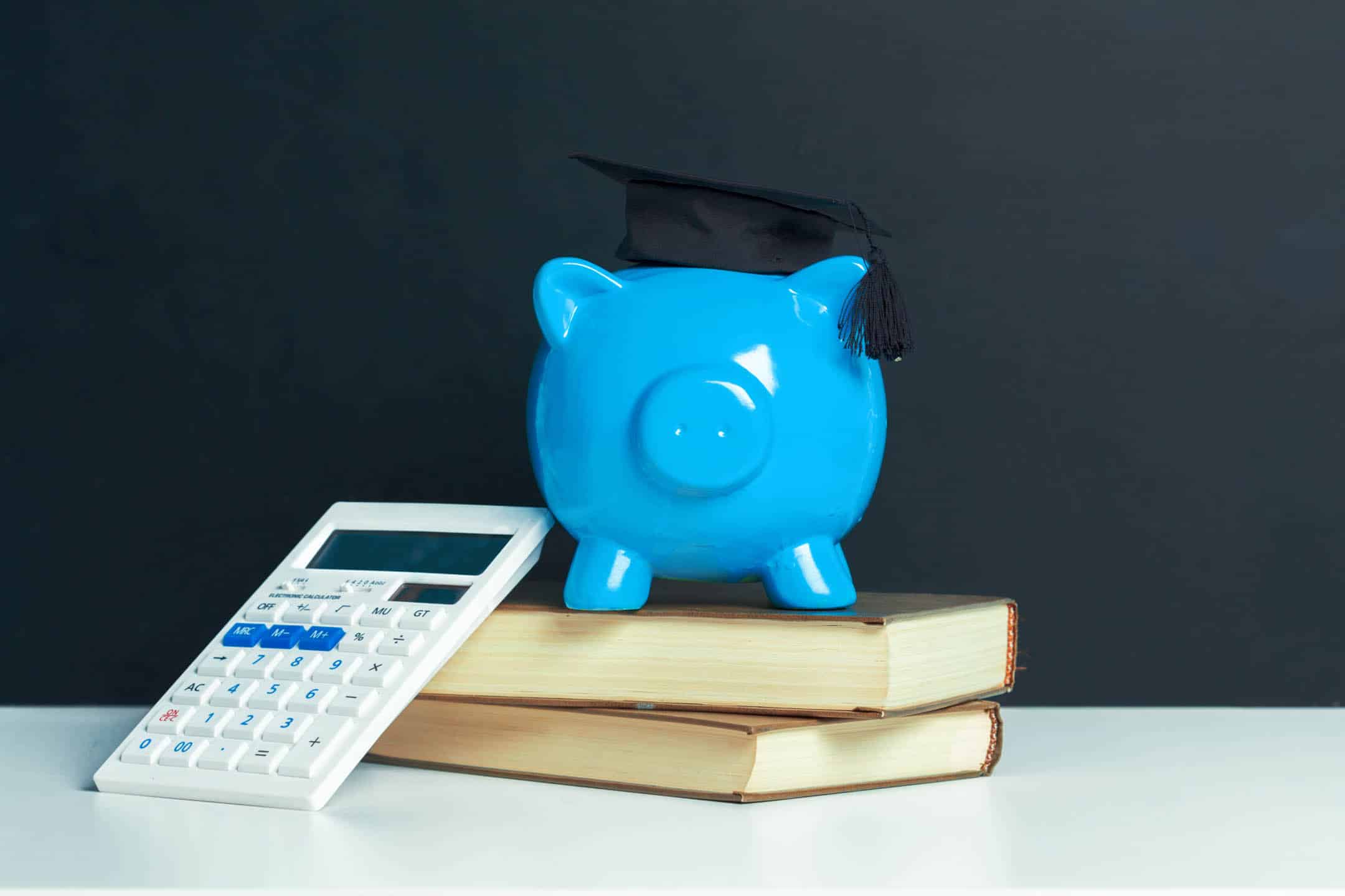Piggy bank with graduation cap, books, and calculator, symbolising financial planning for education.