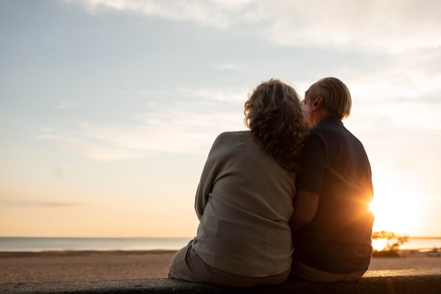 Peaceful elderly couple enjoying sunset by the beach, showcasing retirement lifestyle and outdoor relaxation.